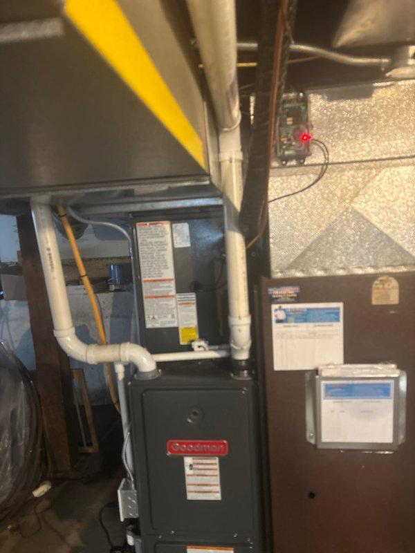 Completed full HVAC system installation including Goodman furnace and air handler in basement utility area, along with outdoor condensing unit positioned on concrete pad against exterior wall. Installed white PVC condensate drain lines, connected refrigerant lines, and verified all electrical connections with proper clearances for maintenance access. System tested and operational upon completion.