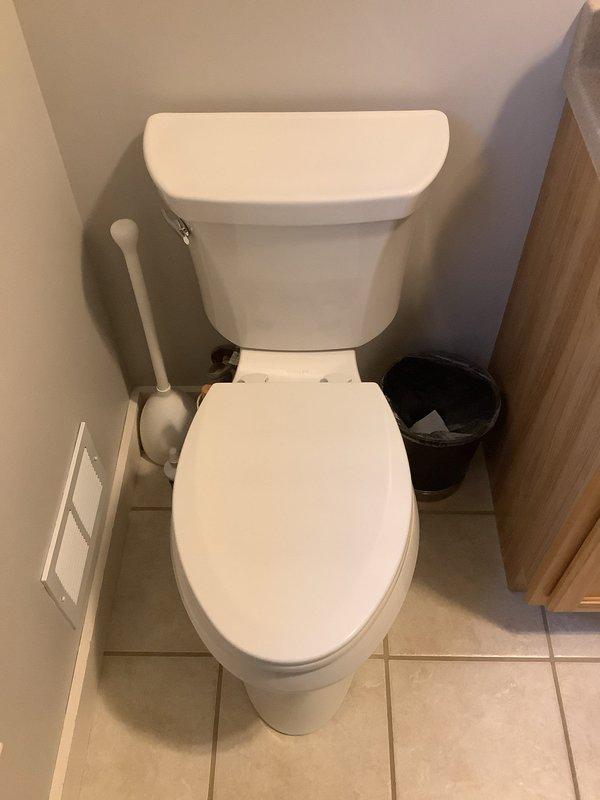 Arrived on-site to provide toilet replacement quote as requested. Performed thorough inspection of existing standard white porcelain toilet in half bathroom. Assessed current installation including floor mounting, water supply connection with braided metal supply line, and flush mechanism components. Documented existing conditions with photographs showing toilet positioning, surrounding space constraints, flooring condition, and internal tank components including flush valve assembly and fill valve. Examined access panel for plumbing accessibility. Reviewed bathroom layout to determine replacement requirements and potential installation considerations. Trip charge waived per management authorization. Provided detailed replacement quote to customer for review and decision.