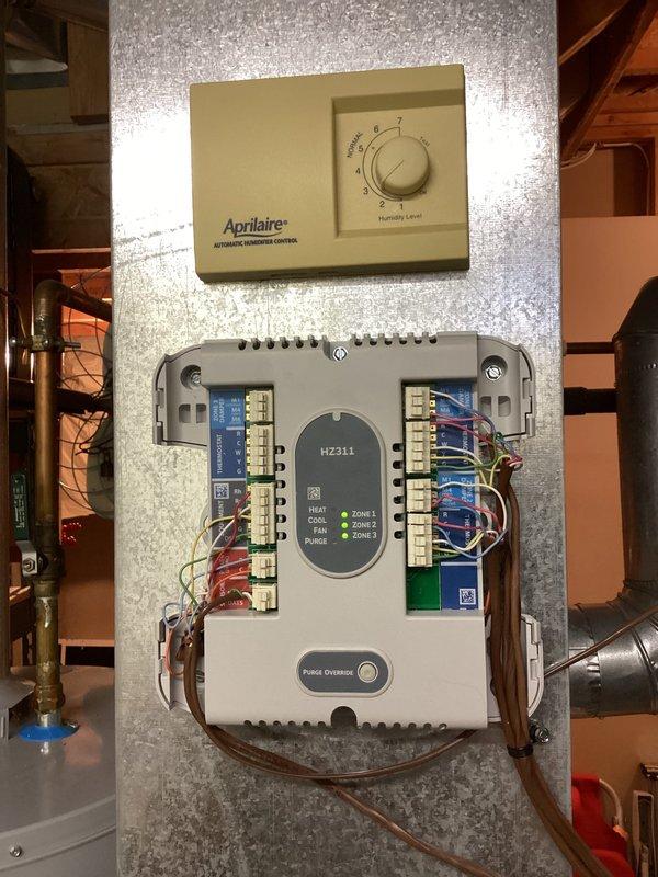 Completed QUOTR-quoted repair involving zone panel thermostat service and exhaust pipe insulation replacement. Installed White-Rodgers digital thermostat on zone system and rewrapped exhaust piping with black foam insulation. Verified proper operation of HZ311 zone control module with Aprilaire humidistat integration across all three heating zones.