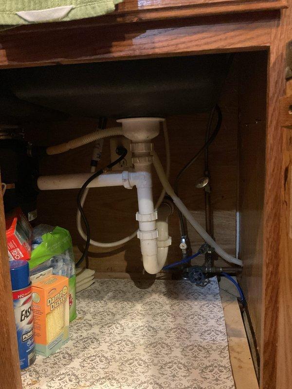 Responded to water leak in basement where pipe was dripping every 4-5 seconds. Inspected plumbing system including basement structural areas and under-sink cabinet connections. Documented existing plumbing configuration including PVC P-trap assembly, drain lines, and exposed piping. Photographed affected areas showing wooden framework, insulation, and plumbing components for service records.