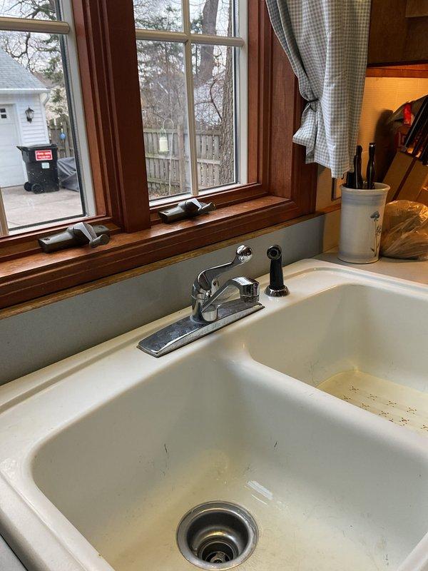 Completed kitchen faucet replacement with customer-supplied fixture. Removed existing chrome faucet assembly and installed new dual-handle chrome faucet with separate spray nozzle, ensuring proper connections and testing for leaks. Job completed without issues in approximately 2 hours.