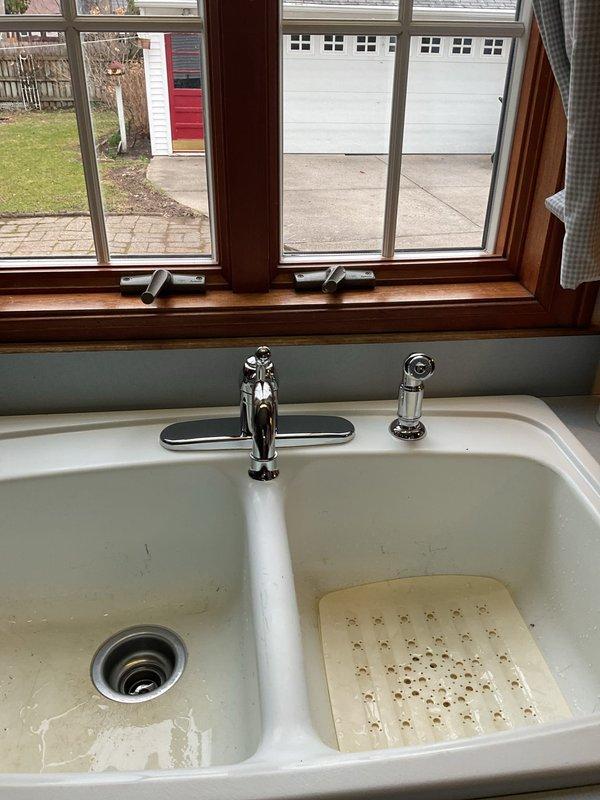 Completed kitchen faucet replacement with customer-supplied fixture. Removed existing chrome faucet assembly and installed new dual-handle chrome faucet with separate spray nozzle, ensuring proper connections and testing for leaks. Job completed without issues in approximately 2 hours.