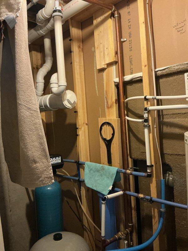 Responded to drainage issue affecting single drain related to water softener backflow in twelve-year-old residence. Upon inspection, identified improper drainage configuration in utility area where water softener discharge line was creating backflow conditions. Cleared obstruction from affected drain line, verified proper flow through PVC drainage system, and confirmed all connections were secure and functioning correctly. Documented plumbing configuration including water supply lines, drainage piping, and water softener installation with photographic evidence for service records.