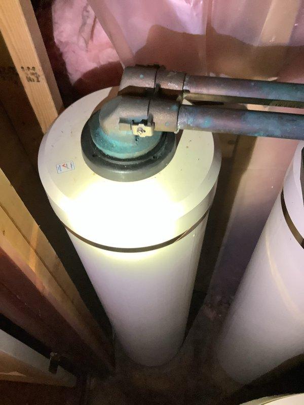 Responded to plumbing leak in 26-year-old residential property and evaluated request for water softener installation. Located and repaired leaking pipe at existing plumbing connections near water heater area. Inspected existing water heater installation, copper supply lines, and shutoff valves for compatibility with proposed water softener system. Documented current plumbing configuration including oxidized copper piping, gate valve assembly, and available connection points for future water treatment equipment integration.