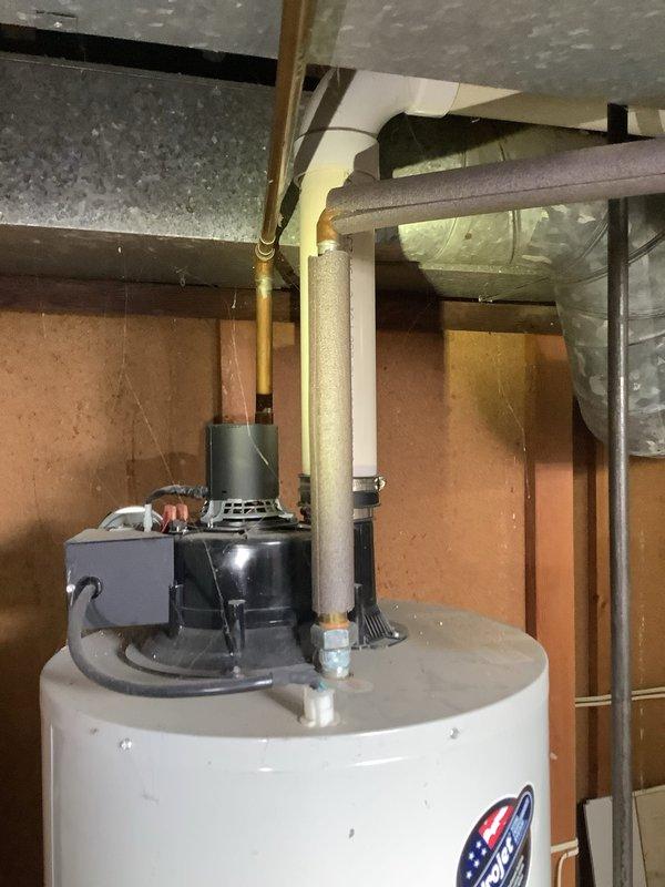 Provided estimate for water heater replacement in unfinished basement utility area. Existing unit is a standard residential water heater with visible plumbing connections, pressure relief valve, copper supply lines, and PVC condensate drainage system with pump assembly. Assessment included evaluation of current installation configuration, structural support requirements, and compatibility with existing plumbing infrastructure for potential replacement.