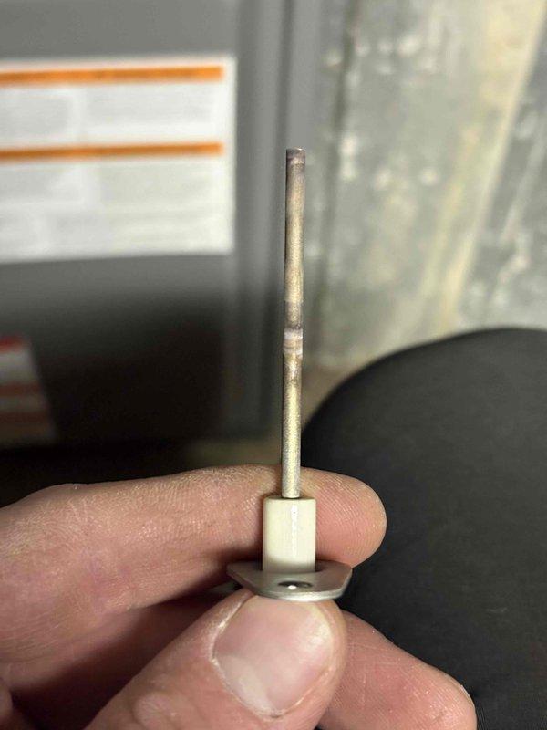 Completed annual heating maintenance on 9-year-old Amana furnace system per club membership agreement. Performed comprehensive tune-up including system inspection, cleaning, and safety checks. Identified failed flame sensor during inspection, as evidenced by heavy oxidation and carbon buildup on the sensor rod. Removed and photographed deteriorated sensor showing significant degradation of the probe element. Component failure would have prevented proper furnace operation and flame detection. Documented sensor condition with detailed photos showing the white ceramic base, threaded mounting assembly, and corroded metal sensing rod for service records.