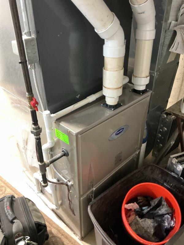 Provided estimate for water heater replacement in residential basement utility room. Assessed existing white cylindrical water heater with Energy Star rating and associated copper supply piping connections. Evaluated current installation configuration including proximity to existing Carrier furnace unit with PVC venting system. Documented existing plumbing connections, electrical components, and clearance requirements for new equipment installation. Photographed current setup to support estimate preparation for complete water heater replacement.