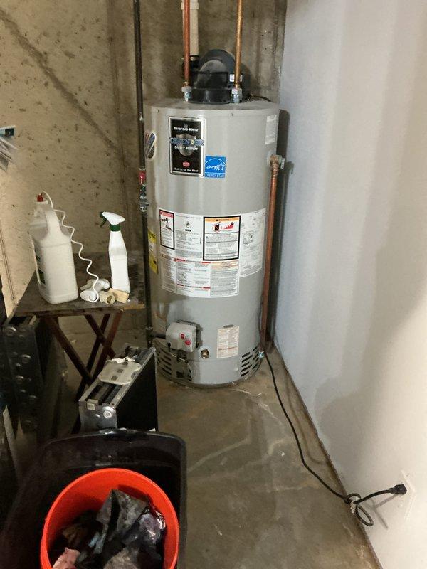 Provided estimate for water heater replacement in residential basement utility room. Assessed existing white cylindrical water heater with Energy Star rating and associated copper supply piping connections. Evaluated current installation configuration including proximity to existing Carrier furnace unit with PVC venting system. Documented existing plumbing connections, electrical components, and clearance requirements for new equipment installation. Photographed current setup to support estimate preparation for complete water heater replacement.