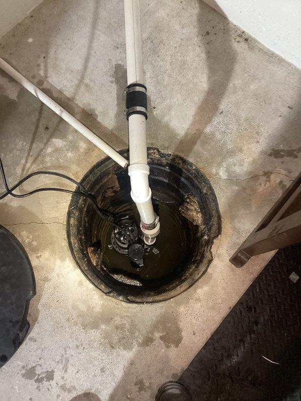 Replaced existing sump pump system in basement sump pit. Removed failed pump unit and installed new submersible sump pump with vertical PVC discharge piping and proper rubber coupling seal at pit exit point. Verified pump operation, tested float switch activation, and confirmed proper drainage through discharge line. System now operational and ready for automatic water removal.