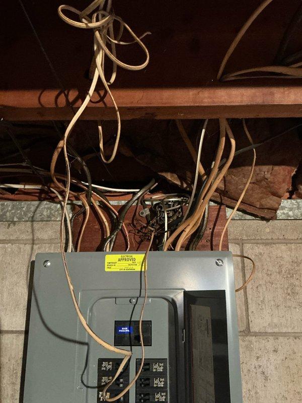 Conducted on-site assessment for new central air conditioning system installation in home without existing central AC equipment. Evaluated electrical infrastructure including main panel box mounted on concrete block wall in basement utility area, noting exposed wooden joists, existing wiring configurations, and available electrical capacity for new HVAC system integration. Documented current electrical panel setup with circuit breaker arrangement and incoming copper wiring to determine compatibility and requirements for new AC unit installation.