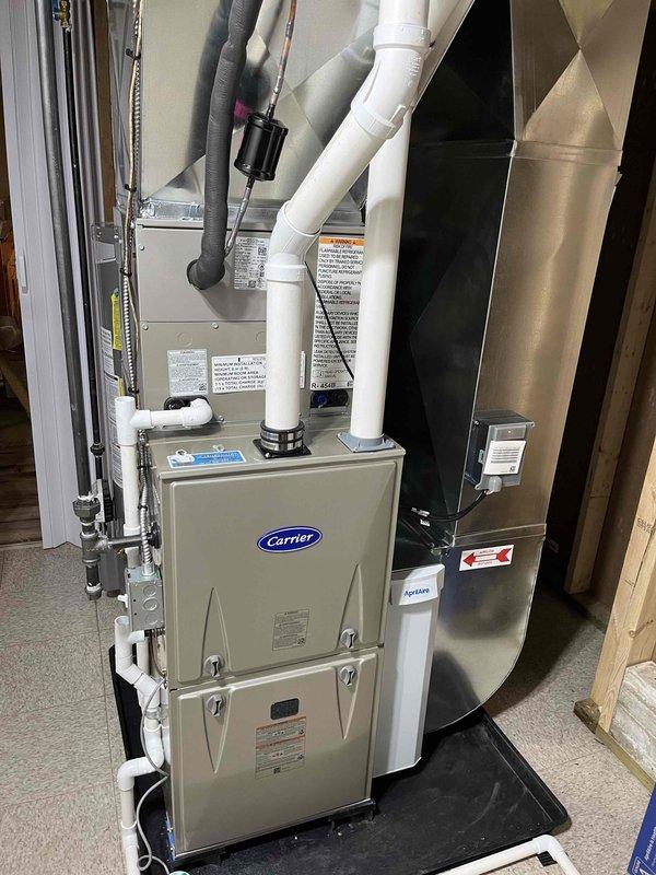 Completed full residential HVAC system replacement including installation of new Carrier furnace and outdoor AC condenser unit. Furnace installed on protective mat in utility area with proper PVC venting, electrical connections, and gas line hookup. Outdoor condenser positioned on concrete pad against exterior wall with electrical disconnect box mounted on siding. All service financing paperwork signed and finalized.