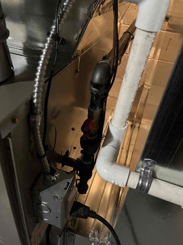 Completed full furnace installation including gas valve control assembly with Baso/Emerson temperature control dial and safety shutoff switch. Integrated new unit with existing HVAC ductwork, plumbing connections, and PVC condensate drainage system in utility space. All components tested and operational, with proper electrical connections established and system verified for safe operation.