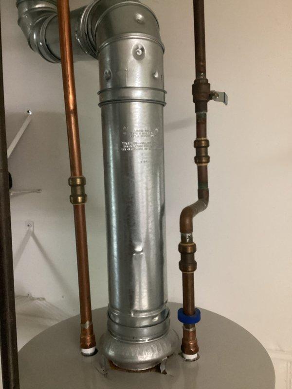 Provided estimate for water heater replacement in residential utility room. Assessed existing galvanized tank water heater with copper supply lines, brass fittings, pressure relief valve, and metal venting system installed on concrete floor with drip pan. Documented current installation configuration including plumbing connections and clearances for replacement recommendations.
