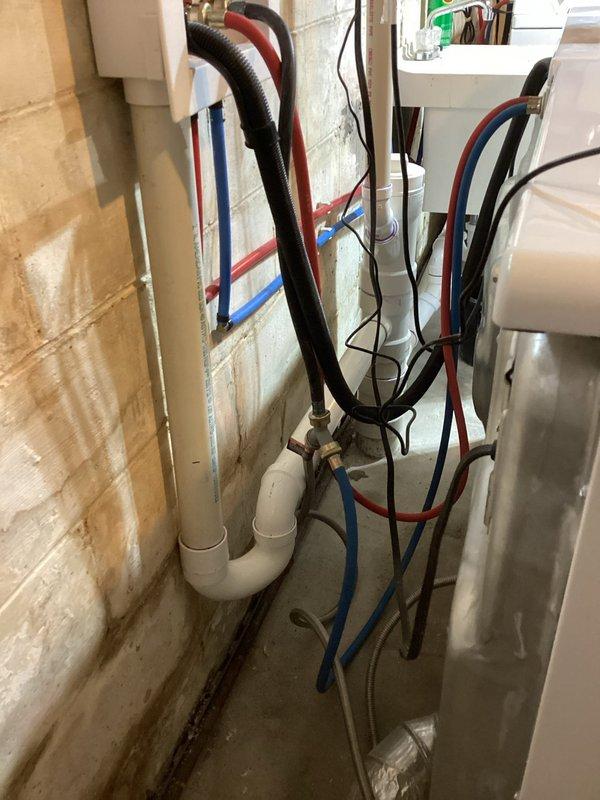 Removed existing improperly configured washing machine drain lines in utility room. Installed new dedicated P-traps for both washing machine and utility sink, with each fixture independently tied into the existing 4-inch drain stack to ensure proper drainage and code compliance.
