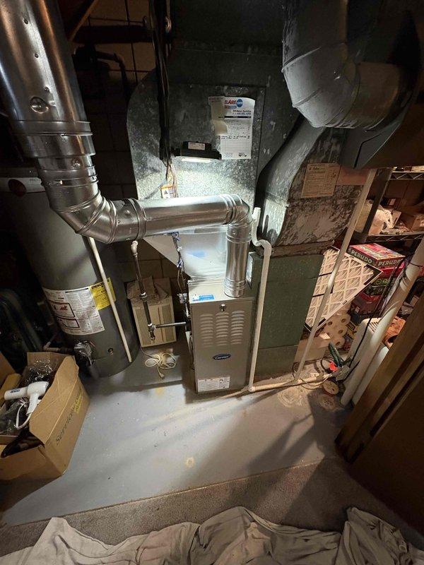 Completed full furnace installation in basement utility area. Installed new white Carrier brand furnace unit with complete ductwork integration, including rigid sheet metal ducts and flexible metallic ducting connections. Connected system to existing green air handler/evaporator coil cabinet mounted on wall. All ductwork properly secured and sealed, with both horizontal and vertical runs completed to ensure proper airflow distribution throughout the residence. Installation completed per specifications, system tested and operational.
