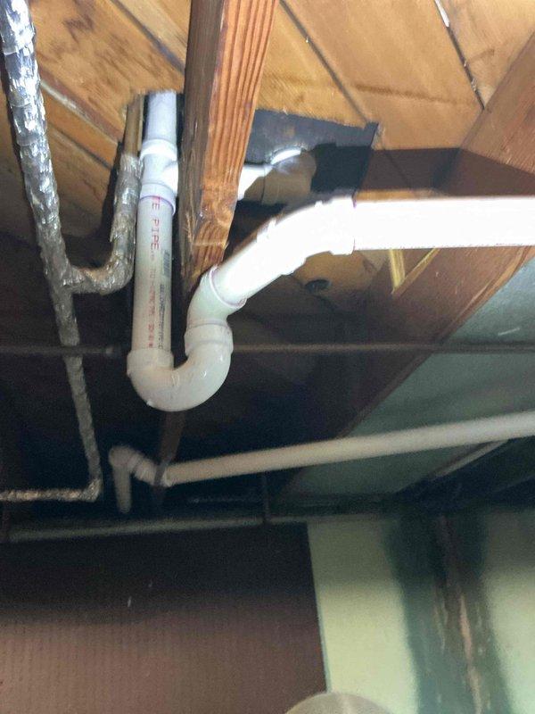 Replaced existing shower valve with new single-handle unit and converted the bathtub drain assembly from tubular fittings to hard pipe configuration for improved durability and code compliance. Work included accessing plumbing through attic space, installing new valve trim at tub/shower fixture, and reconfiguring drain P-trap with PVC hard pipe connections.