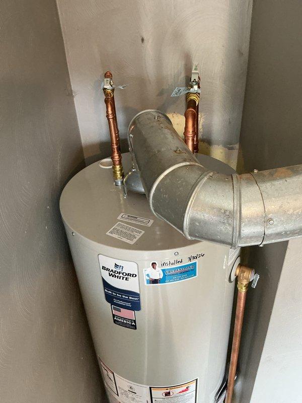 Completed installation of a 40-gallon natural gas water heater, tall model, manufactured by Bradford White. Connected copper supply lines with compression fittings and shut-off valves, installed galvanized metal venting ductwork with proper elbow configuration for exhaust, and ensured brass drain valve accessibility. All safety labels, manufacturer specifications, and warning placards were verified in place, and unit was tested for proper operation and compliance with code requirements.