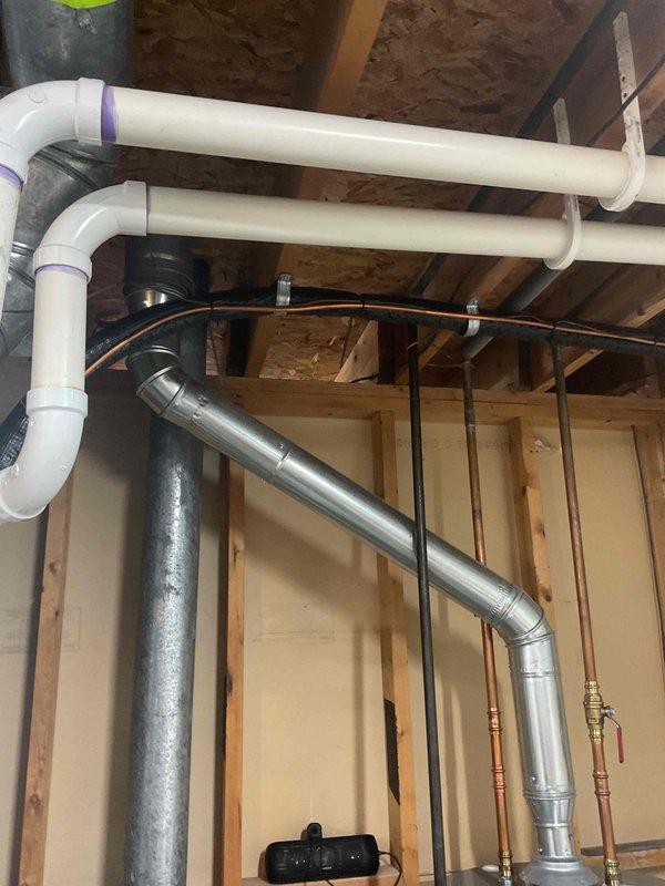 Evaluated existing Rheem water heater venting configuration in unfinished basement to determine feasibility of converting from vertical roof vent to horizontal side-wall vent termination. Inspected current Category I atmospheric vent system with metal exhaust pipe extending upward from unit, assessed clearances to combustible materials, and reviewed proximity to existing HVAC ductwork and PVC plumbing lines. Advised client on code requirements, structural considerations, and potential need for power venting conversion depending on appliance specifications and horizontal run length requirements.