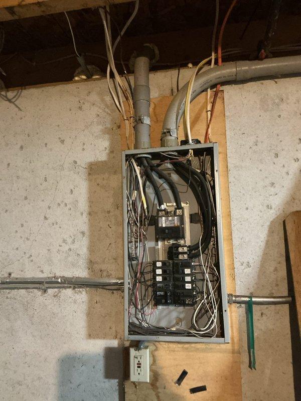 Conducted electrical estimate for running power to an outbuilding from existing main service panel. Assessed current panel capacity, circuit breaker availability, and wire routing requirements from basement-mounted electrical panel through structure to proposed outbuilding location. Documented existing panel configuration with multiple circuit breakers in dual columns, main disconnect assembly, and current wiring arrangements including conduit pathways along wooden framing. Photographed panel interior showing circuit organization, available breaker spaces, and wire management to determine feasibility and material requirements for new dedicated circuit installation to outbuilding.