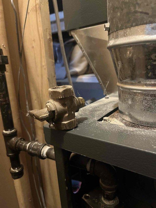 Responded to gas leak call on 2017 Goodman furnace where gas odor persisted following recent valve installation. Upon arrival, confirmed furnace remained operational but gas smell was present in mechanical area. Performed comprehensive inspection of gas supply line, including newly installed red-handled ball valve and brass compression fittings connected to black gas piping. Documented all valve connections, gas line routing, and furnace installation with detailed photographs for service records. Verified proper valve positioning and examined all threaded connections for potential leak sources. Inspected gas valve assembly mounted on furnace platform, including hexagonal valve body and control mechanism. Assessed copper piping, ductwork connections, and surrounding utility area for any additional concerns related to gas odor complaint.
