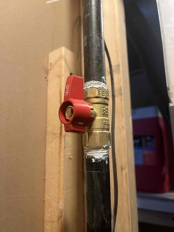 Responded to gas leak call on 2017 Goodman furnace where gas odor persisted following recent valve installation. Upon arrival, confirmed furnace remained operational but gas smell was present in mechanical area. Performed comprehensive inspection of gas supply line, including newly installed red-handled ball valve and brass compression fittings connected to black gas piping. Documented all valve connections, gas line routing, and furnace installation with detailed photographs for service records. Verified proper valve positioning and examined all threaded connections for potential leak sources. Inspected gas valve assembly mounted on furnace platform, including hexagonal valve body and control mechanism. Assessed copper piping, ductwork connections, and surrounding utility area for any additional concerns related to gas odor complaint.