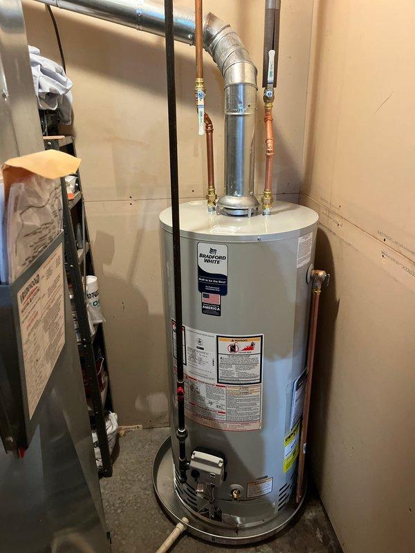 Completed installation of a 40-gallon Bradford White natural gas water heater in residential utility closet. Connected copper supply piping with brass fittings, installed gas supply line with electronic control valve, and properly vented unit with metallic exhaust flue. All connections tested and verified operational per manufacturer specifications.