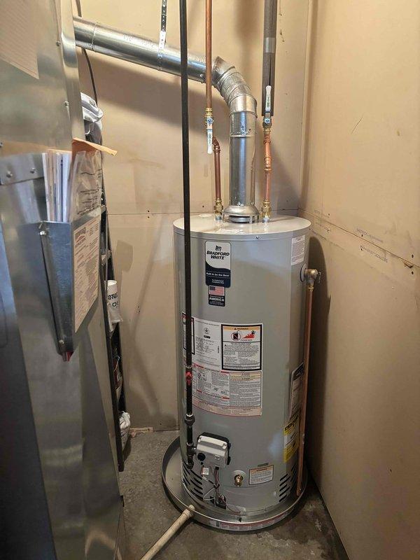 Completed installation of a 40-gallon Bradford White natural gas water heater in residential utility closet. Connected copper supply piping with brass fittings, installed gas supply line with electronic control valve, and properly vented unit with metallic exhaust flue. All connections tested and verified operational per manufacturer specifications.