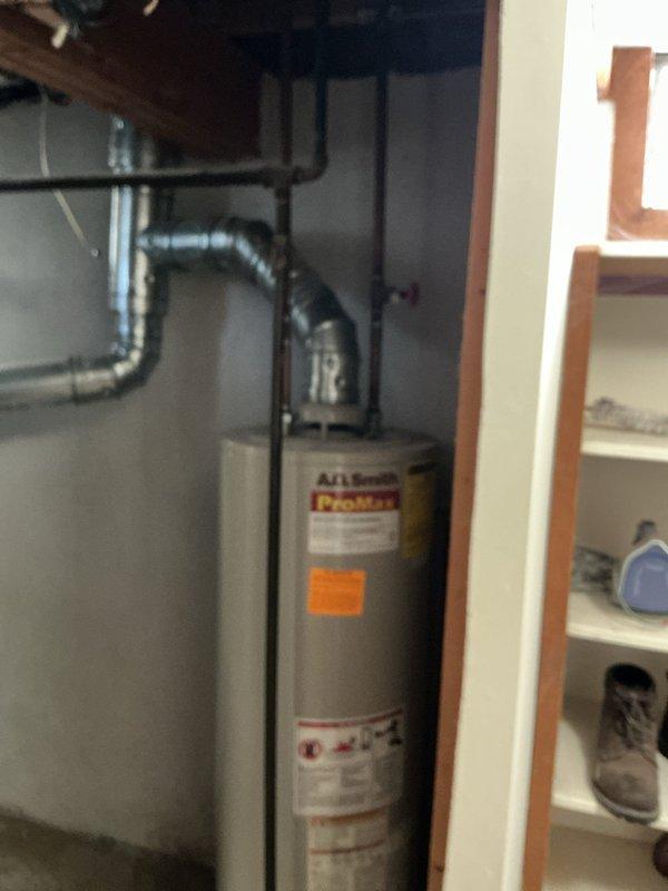 Conducted on-site assessment of existing A.O. Smith ProMax tank-style water heater installation in residential utility area to provide comprehensive estimate for water heating system replacement options. Documented current equipment configuration, including gas supply lines, venting system with flexible ductwork, plumbing connections, and spatial constraints within the utility closet to evaluate feasibility of both traditional tank-type and tankless water heater installations.