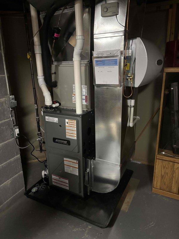 Successfully completed full installation of new furnace and water heater system in residential basement utility area. Installed dark gray forced-air furnace unit with proper venting configuration, including white PVC exhaust piping routed to ceiling-mounted black ductwork. Mounted furnace on protective drip pan per code requirements. Connected all electrical conduit and wiring to furnace unit.

Installed Bradford White water heater adjacent to furnace system with copper supply line connections and metallic elbow duct at top of unit. Secured all gas lines and water lines to wall structure with proper mounting hardware. Verified all manufacturer specifications and safety labels are visible and intact on both units.

Completed all ductwork connections between furnace and air distribution system. Ensured proper clearances maintained around both units for service access and code compliance. System tested and confirmed operational upon completion.