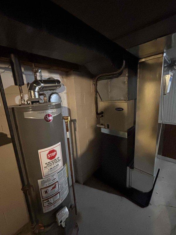Completed full furnace replacement in basement mechanical room. Installed new Carrier HVAC unit with proper venting configuration using white PVC piping routed horizontally along upper wall section. Positioned condensate drain pan at base of unit on concrete floor. Verified all ductwork connections to existing black ductwork system and ensured proper clearances from adjacent water heater. System tested and operational upon completion.