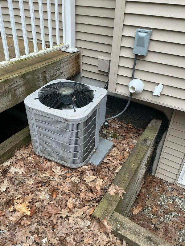 Provided estimate for air conditioning system replacement at residential property. Inspected existing outdoor condenser unit with white cabinet and black fan grille, noting unit positioned against house exterior on concrete pad within timber-framed recessed area. Customer expressed interest in current promotional offerings for new AC system installation.