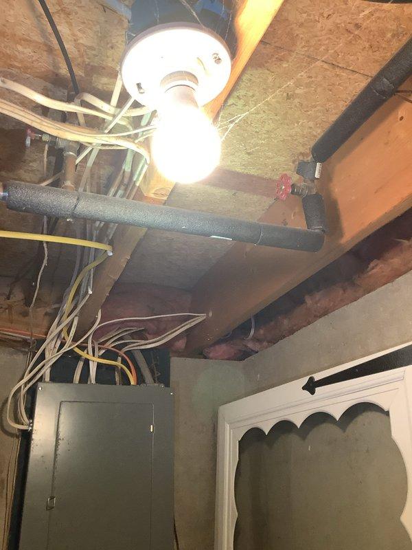 Conducted on-site assessment for water softener installation in residential property. Evaluated existing plumbing infrastructure in unfinished basement area, documenting current electrical panel location, exposed ceiling joists with OSB sheathing, and existing mechanical systems including copper piping and PVC conduit runs. Photographed installation area to determine optimal placement for water conditioning equipment and identify necessary connections to main water supply line. Assessed accessibility for future equipment installation and maintenance, noting proximity to electrical service panel for required dedicated circuit installation.