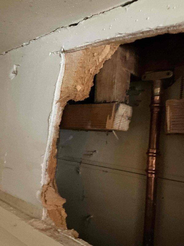 Responded to plumbing leak caused by improper DIY shower component installation. Opened drywall to access plumbing system and identified faulty connections in copper supply lines and brass valve assembly. Repaired leaking fittings, verified proper installation of shower components, and confirmed all connections were secure and leak-free before closing access point.