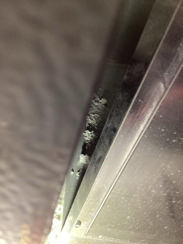 Completed annual heating maintenance on 9-year-old furnace and humidifier system. During inspection, discovered significant frost and ice crystal accumulation on air handler components and metal surfaces, indicating abnormal temperature regulation or airflow restriction. The frost buildup was concentrated around component seams, metal plates, and a circular port opening, with white crystalline deposits extending along equipment edges. Documented conditions with photographs showing the extent of ice formation on gray metal components and adjacent ductwork. The frost accumulation pattern suggests potential issues with condensate drainage, refrigerant flow, or humidity control that will require further diagnosis and correction to prevent system damage and ensure proper heating season operation.
