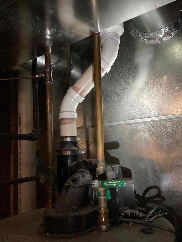 Responded to water leak service call and conducted thorough inspection of residential water heating system. Upon arrival, examined 40-gallon Bradford White natural gas water heater manufactured in 2014 and associated plumbing infrastructure. Inspected all visible connections, supply lines, and discharge piping for signs of active leakage or moisture accumulation. Evaluated sump pump system and drainage assembly located in basement utility area, including PVC discharge piping with multiple directional changes and copper supply lines running along structural framing. Verified proper operation of pump unit and checked all pipe joints and fittings for integrity. Documented equipment condition and installation configuration through photographic records showing water heater specifications, safety labeling, and mechanical systems layout including flexible ductwork and metallic components in utility space.