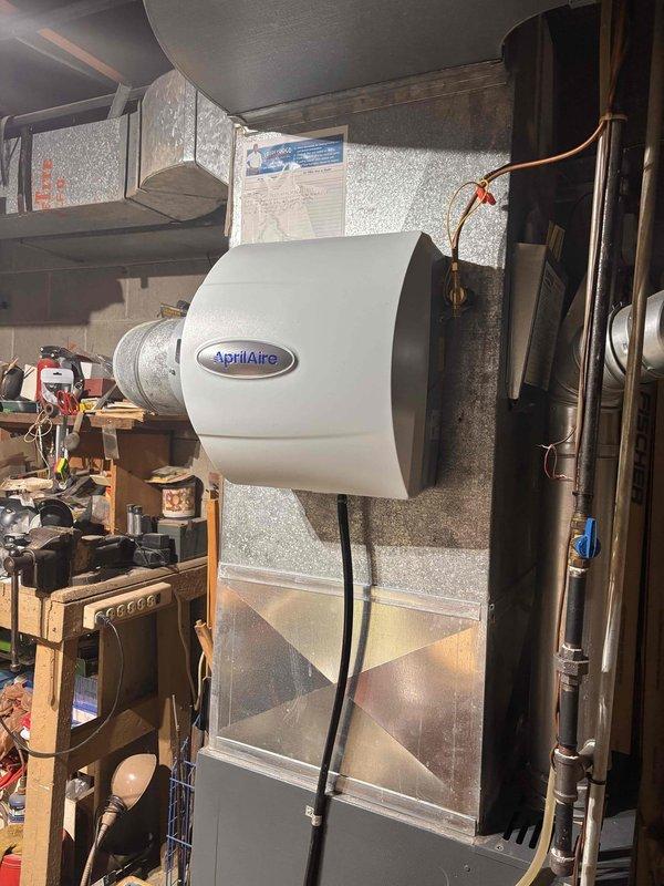 Completed installation of AprilAire whole-home humidifier unit mounted to main supply ductwork. Connected electrical wiring and water supply lines to humidifier, integrated unit with existing HVAC system to provide automated humidity control throughout the residence. System tested and operational upon departure.