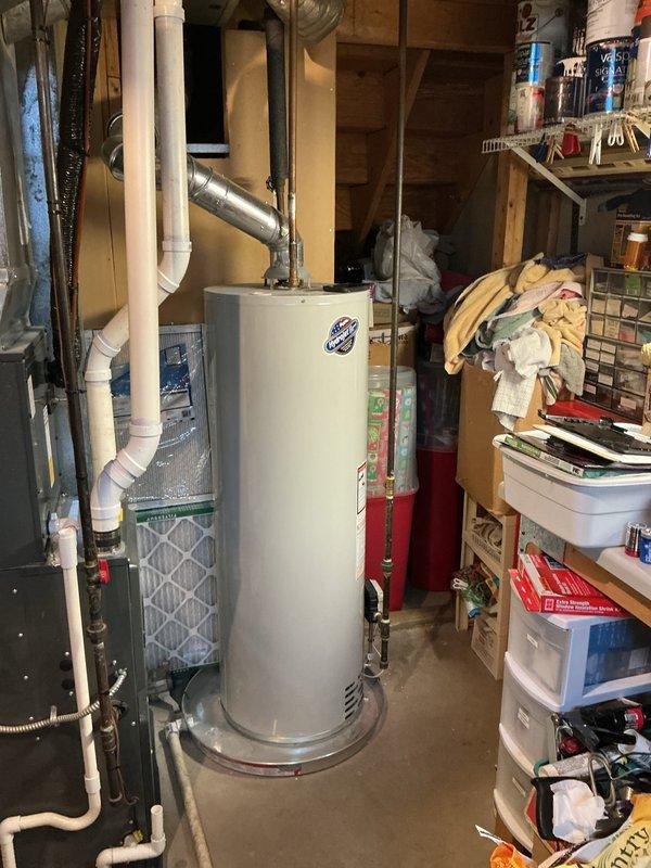 Completed on-site estimate for water heater replacement in residential basement utility area. Inspected existing conventional tank-style water heater with overhead venting system, assessed current plumbing connections including copper supply lines and metallic exhaust vent pipe, documented equipment specifications and installation configuration, photographed unit and surrounding mechanical systems including adjacent HVAC equipment, and provided comprehensive replacement options and recommendations to customer.