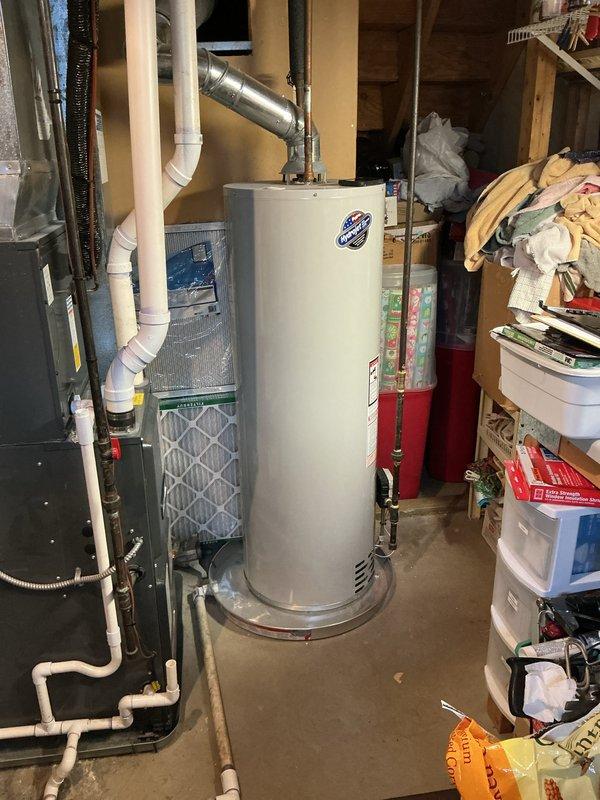 Completed on-site estimate for water heater replacement in residential basement utility area. Inspected existing conventional tank-style water heater with overhead venting system, assessed current plumbing connections including copper supply lines and metallic exhaust vent pipe, documented equipment specifications and installation configuration, photographed unit and surrounding mechanical systems including adjacent HVAC equipment, and provided comprehensive replacement options and recommendations to customer.