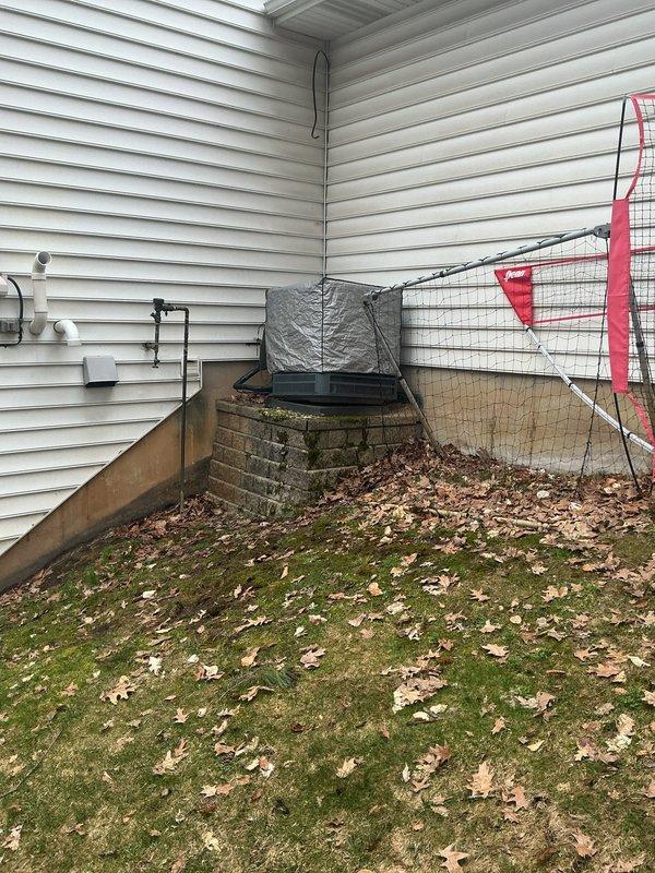 Completed annual cooling maintenance on 13-year-old Goodman AC unit. Upon arrival, found unit tilted on deteriorated brick base with significant leaf debris accumulation around condenser coils. Cleaned condenser coils and removed leaf buildup from base area. Inspected brick foundation and documented structural concerns with base stability. Performed standard tune-up procedures including system performance testing. Photographed tilted unit position and compromised base for customer review. Unit operational but recommend base leveling and repair to prevent further settling and potential refrigerant line stress.