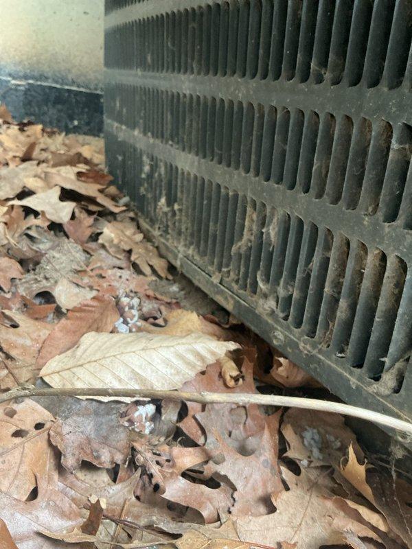 Completed annual cooling maintenance on 13-year-old Goodman AC unit. Upon arrival, found unit tilted on deteriorated brick base with significant leaf debris accumulation around condenser coils. Cleaned condenser coils and removed leaf buildup from base area. Inspected brick foundation and documented structural concerns with base stability. Performed standard tune-up procedures including system performance testing. Photographed tilted unit position and compromised base for customer review. Unit operational but recommend base leveling and repair to prevent further settling and potential refrigerant line stress.