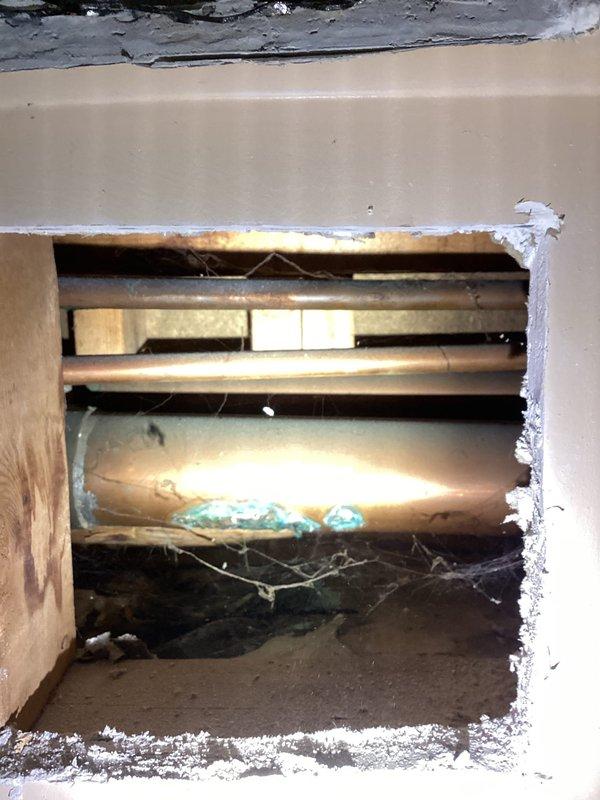 Responded to callback for persistent kitchen sink leak. Upon arrival, conducted thorough inspection of previously repaired plumbing connections. Investigation required accessing crawl space beneath kitchen area to identify source of ongoing water intrusion. Cut access openings in ceiling and wall drywall to expose plumbing lines and structural components. Inspection revealed leak originating from supply lines or drain connections above crawl space. Documented conditions with photos showing exposed floor joists, insulation, and structural framing. Access points created will allow for proper repair of leaking plumbing components and subsequent restoration of drywall surfaces.