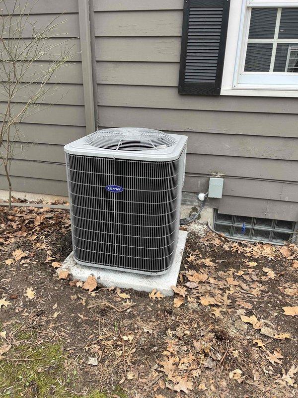 Completed full HVAC system installation including new furnace and air conditioning unit in residential basement mechanical room. Installed dark gray furnace with white PVC venting, connected to silver metallic evaporator coil and black flexible ductwork routed along ceiling joists. Mounted outdoor condensing unit on concrete pad against exterior wall with proper refrigerant line connections, electrical disconnect, and secured copper line set penetration through siding.