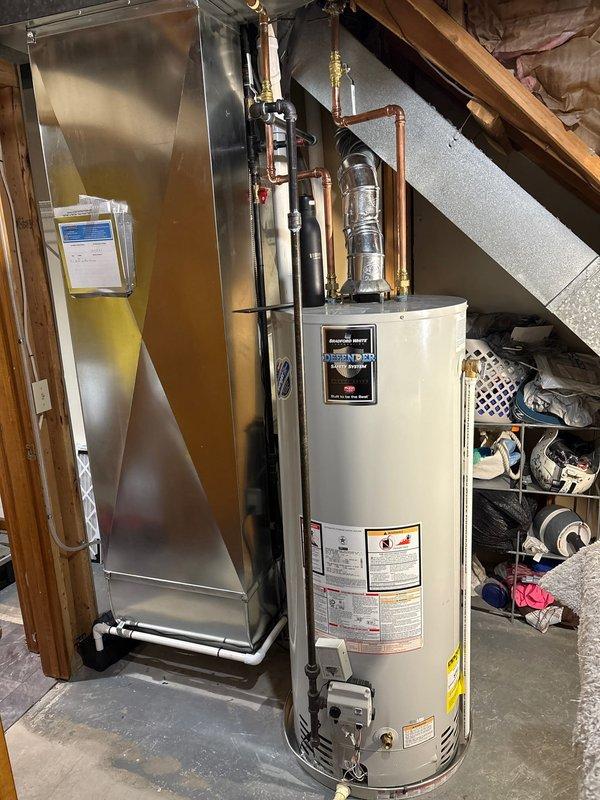 Completed full furnace replacement in residential utility closet. Installed new dark gray furnace unit with proper vertical positioning and secured all manufacturer safety labels. Connected silver metal supply ductwork to unit discharge with appropriate angles and sealed all joints. Installed white PVC condensate drain and vent piping along right side of unit with secure mounting. Verified proper clearances from adjacent water heater and surrounding walls per code requirements. Tested all electrical connections, gas line integrity, and airflow distribution. System commissioned and operational, meeting manufacturer specifications.