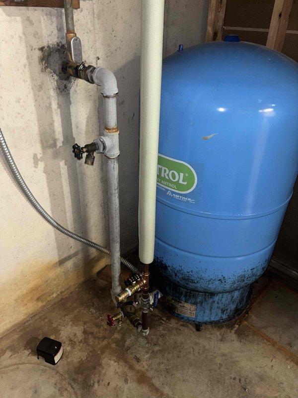 Responded to water pressure complaint following recent repair work. Inspected whole-house water treatment system including dual blue filter housings, water softener tank, and pressure tank. Identified potential restriction in filtration system causing reduced flow. Evaluated filter cartridges for blockage, checked valve positions, and verified proper system operation. Documented existing equipment condition and configuration with photos for service records.