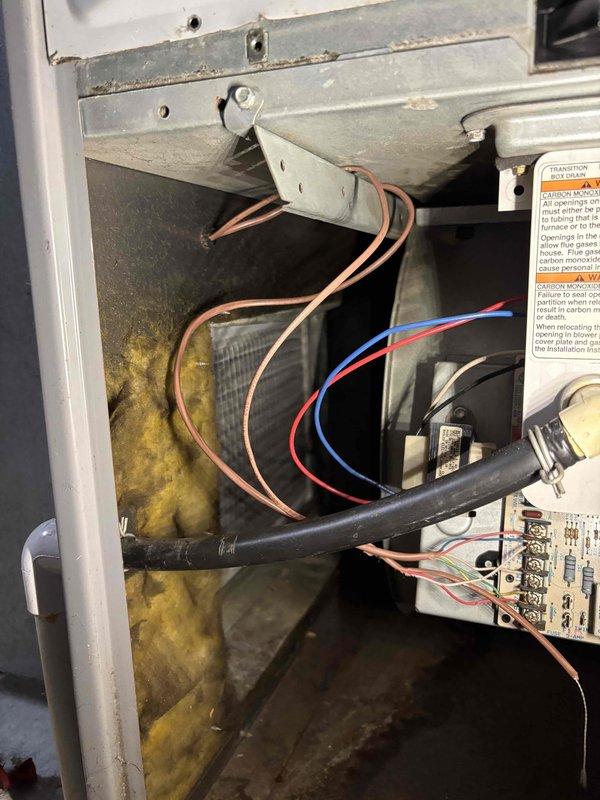 # Furnace No Heat - Blower Fan Failure

Responded to no heat call on 14-year-old Comfort-Aire furnace with blower fan not operating. Upon arrival, confirmed furnace was calling for heat but blower motor failed to engage. Removed access panel and performed visual inspection of internal components and control board.

Identified degraded fiberglass insulation with moisture staining in blower compartment, indicating potential condensate drainage issues or humidity exposure over time. Inspected control board wiring and terminal connections - found multiple wire terminations with exposed copper conductors and loose connections at terminal blocks. 

Traced blower motor circuit from control board through wire harness. Tested voltage at blower motor terminals and confirmed no power delivery to motor during heat call. Verified control board outputs and relay operation. Determined control board relay failure preventing blower motor energization.

Discussed repair options with customer. Customer a