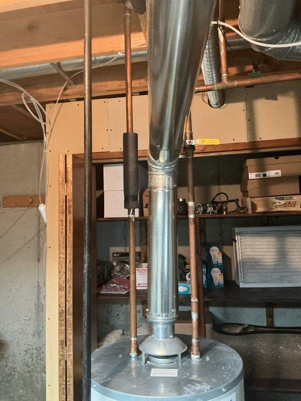 Responded to emergency call for aggressively leaking water heater with complete loss of hot water. Upon arrival, identified Bradford White 40-gallon automatic storage water heater with active leak in basement utility area. Immediately shut off water supply and gas line to unit to prevent further water damage and ensure safety. Documented equipment condition with photographs showing water heater installation, surrounding plumbing connections including copper supply lines with foam insulation, galvanized flue pipe, and proximity to HVAC equipment. Verified unit specifications from manufacturer data plate and assessed overall system configuration in unfinished basement space with exposed joists and concrete flooring.