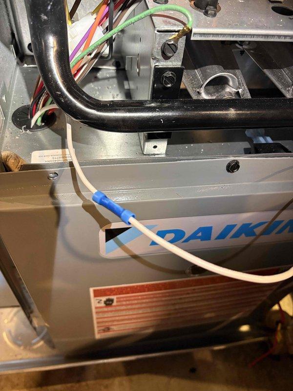 Completed annual heating maintenance on Fraser-Johnston furnace installed in 2018. During inspection, discovered damaged wiring with exposed copper conductors and compromised insulation on the Daikin HVAC unit's electrical system. Documented wire damage with photos showing corrosion at the exposure point and captured internal component layout including refrigerant lines, wire harness routing, and mounting hardware for service records.