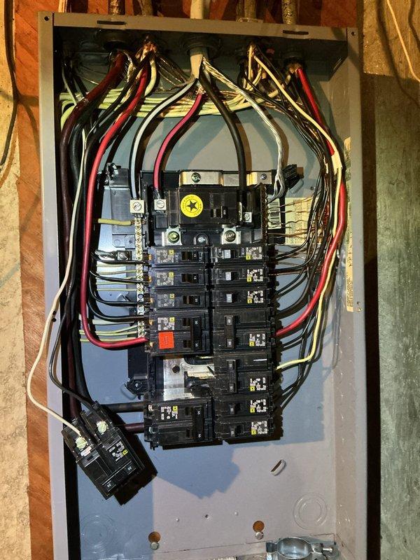 Responded to report of small fire or smoke incident at electrical panel connected to newly installed AC unit in sixty-year-old residence. Upon arrival, inspected main electrical panel and surrounding area for signs of overheating, arcing, or fire damage. Removed panel cover to conduct thorough internal inspection of circuit breakers, bus bars, and all wire connections. Examined all incoming service conductors and branch circuit wiring for heat damage, discoloration, or compromised insulation. Verified proper torque on all breaker connections and main lugs. Inspected grounding and bonding connections for integrity. Checked for any signs of moisture intrusion, corrosion, or loose connections that may have contributed to the incident. Photographed panel interior showing dual rows of circuit breakers, main service conductors, and overall wiring configuration for documentation purposes. Verified no active fire hazards or immediate safety concerns present within the electrical panel at time 