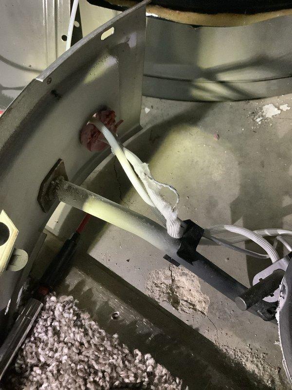 Responded to emergency service call for 6-year-old Rheem water heater not heating properly. Upon arrival, confirmed thermopile was displaying two red indicator lights, indicating low voltage output below operational threshold. Performed diagnostic testing of gas control valve and thermopile assembly. Inspected burner chamber and pilot assembly for proper operation and flame characteristics. Accessed internal components through service panel, noting accumulated debris in combustion chamber area. Verified proper venting and air flow through the unit. Tested thermopile voltage output and determined replacement necessary to restore proper heating function. Documented equipment condition with photographs showing internal cabinet components, access panel with visible corrosion on frame, and debris accumulation requiring cleaning. Provided recommendations for thermopile replacement to restore unit to full operational status.