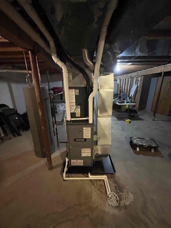 Completed full system installation of new furnace and air conditioning unit. Indoor furnace unit installed in basement mechanical room with proper ductwork connections, including flexible and rigid ducting routed through ceiling joists. Outdoor condenser unit positioned on concrete pad against exterior wall with appropriate clearances, electrical connections completed, and refrigerant lines properly installed. All components tested and verified operational upon completion of installation.